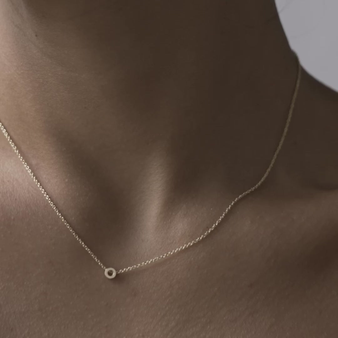 Solid gold and sterling silver jewellery: Close up video of a model wearing our signature 9ct yellow gold Tiny Letter O Charm Necklace on a 40cm cable chain