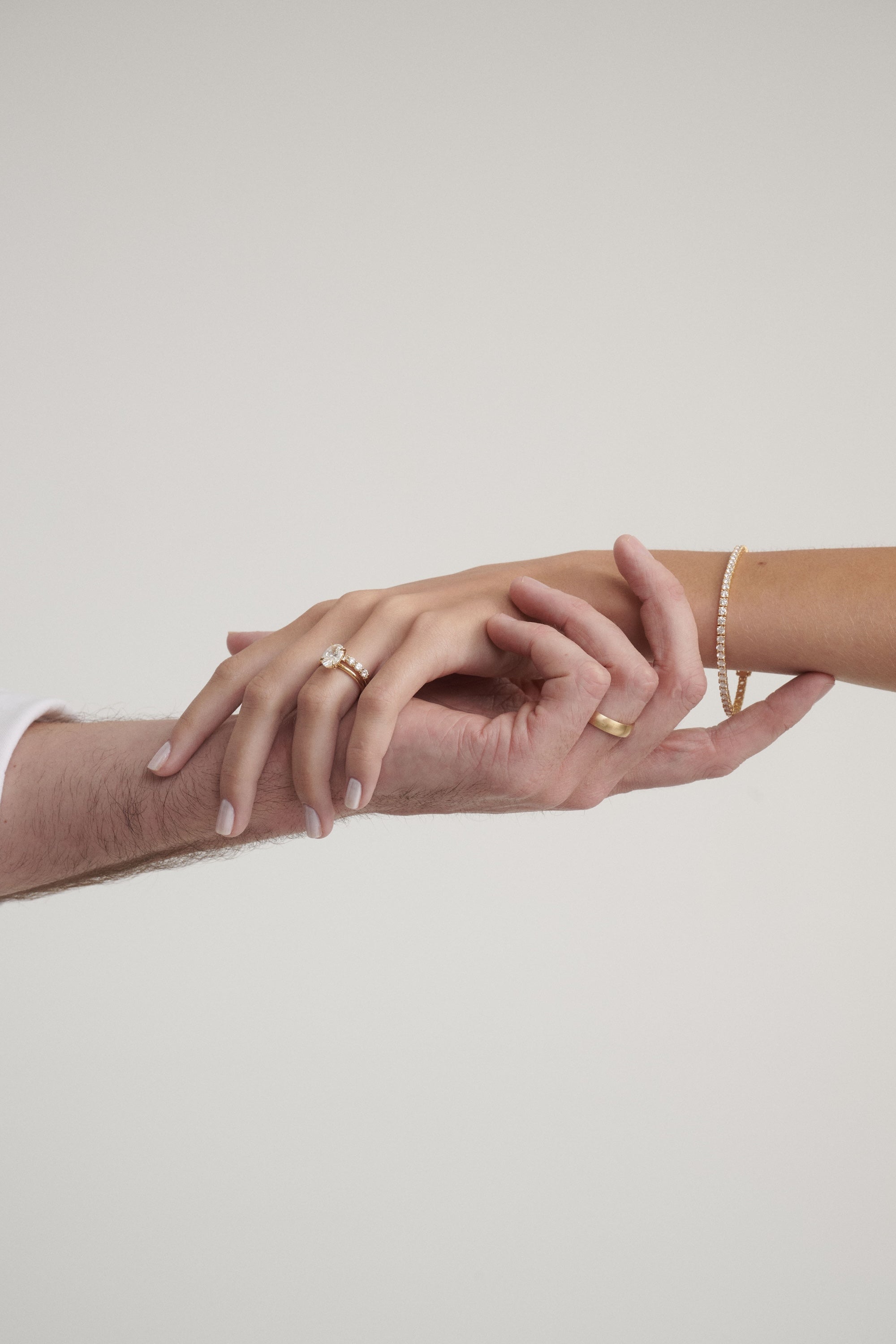 Two hands with rings on a plain background