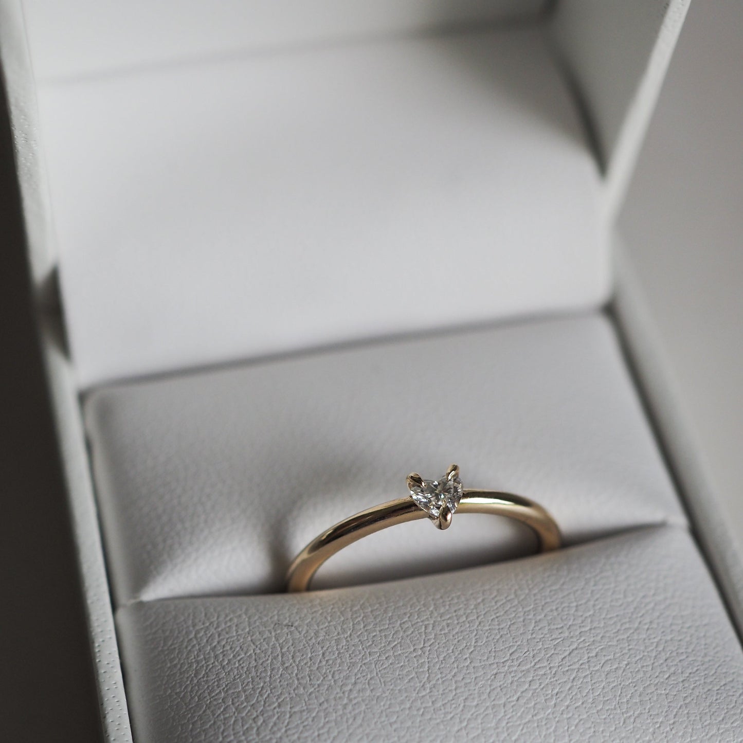 Elegant minimalist gold ring with a small marquise diamond, showcased in an open white jewellery box, indicating luxury and sophistication.