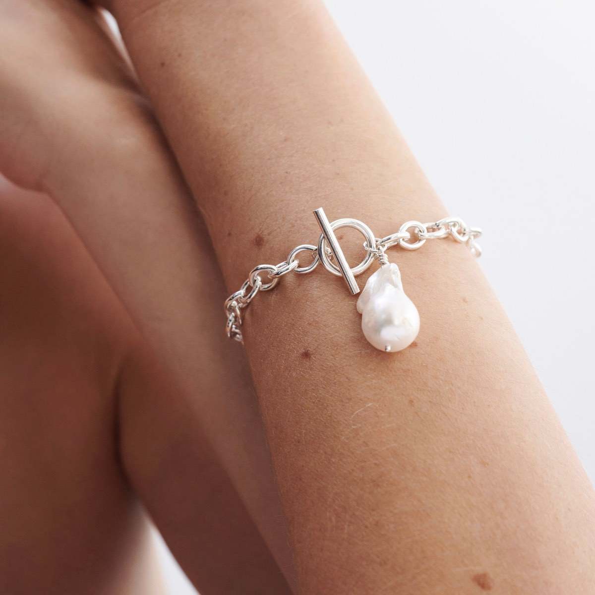 Hand wrapped freshwater baroque pearl: Close up of a model wearing a beautiful sterling silver baroque pearl fob bracelet