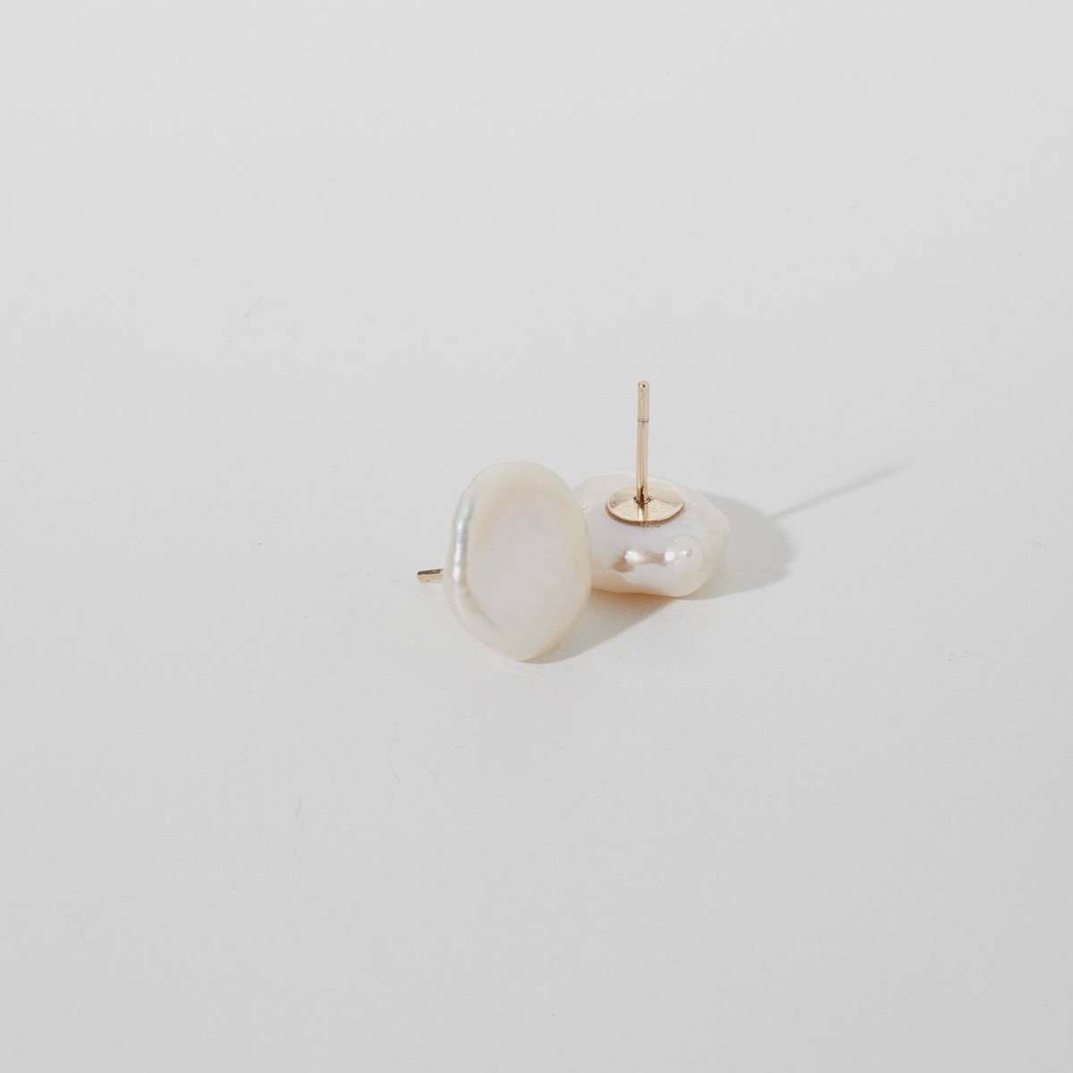 Flat lay of our signature large baroque pearl studs in 9ct yellow gold.