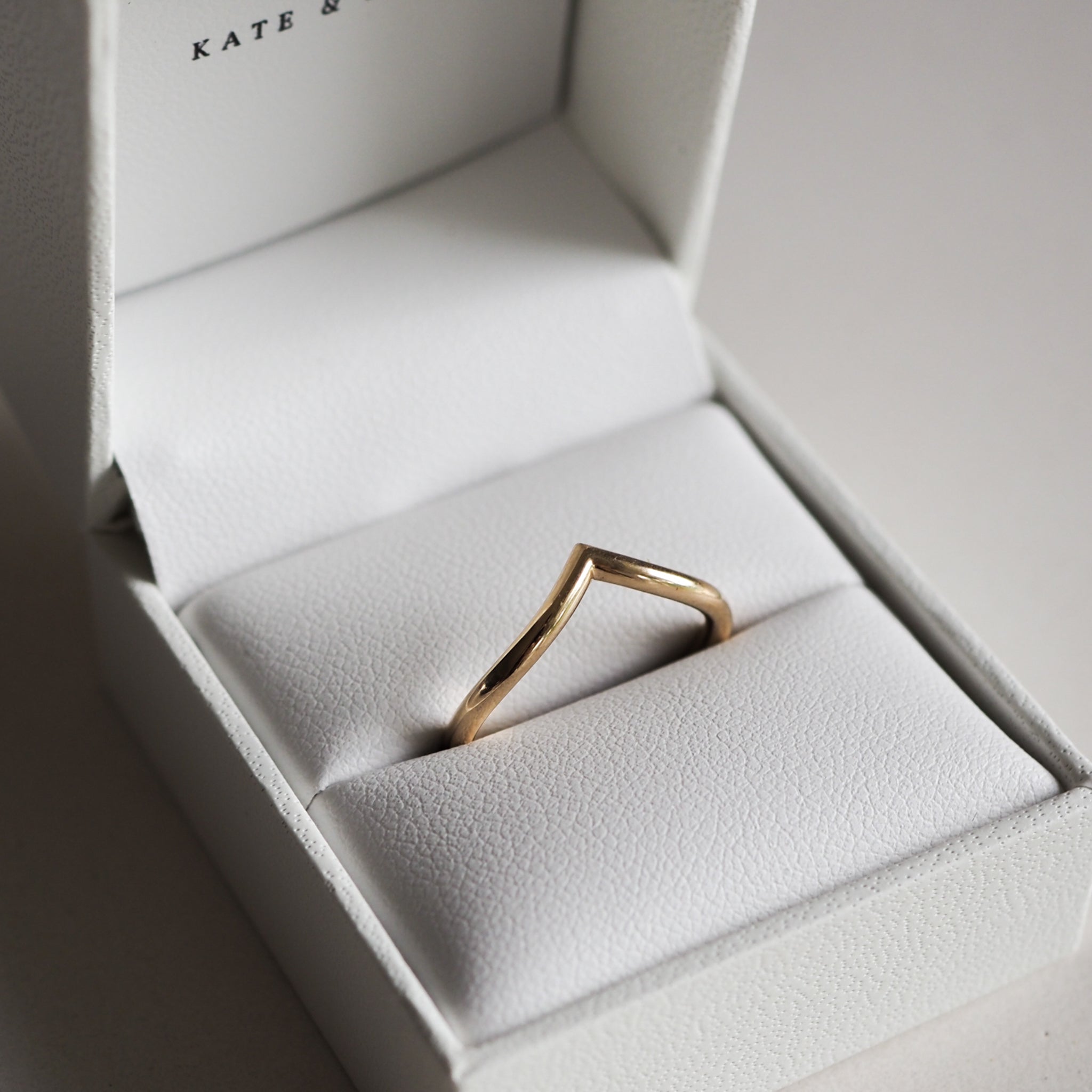 Gold V-shaped ring in a white jewellery box; elegant minimalist design perfect for luxury fashion styling.
